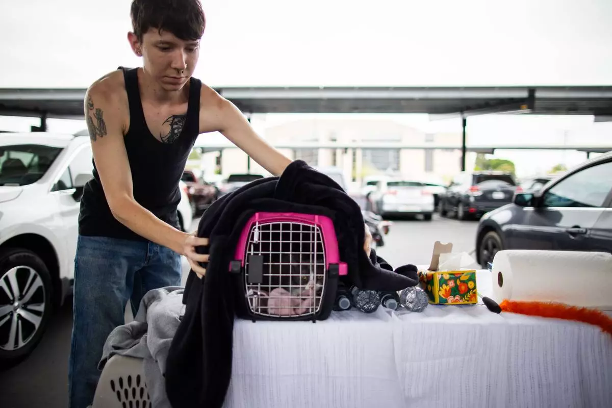 An evacuee gather their pets and belongings at the John F. Kennedy High School in La Palma, Calif., on Sunday, May 24, 2026. (AP Photo/Ethan Swope)