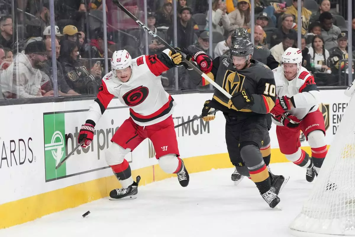 FILE - Carolina Hurricanes left wing Eric Robinson (50) and Vegas Golden Knights center Colton Sissons (10) battle for the puck during the first period of an NHL hockey game, Oct. 20, 2025, in Las Vegas. (AP Photo/Candice Ward, file)