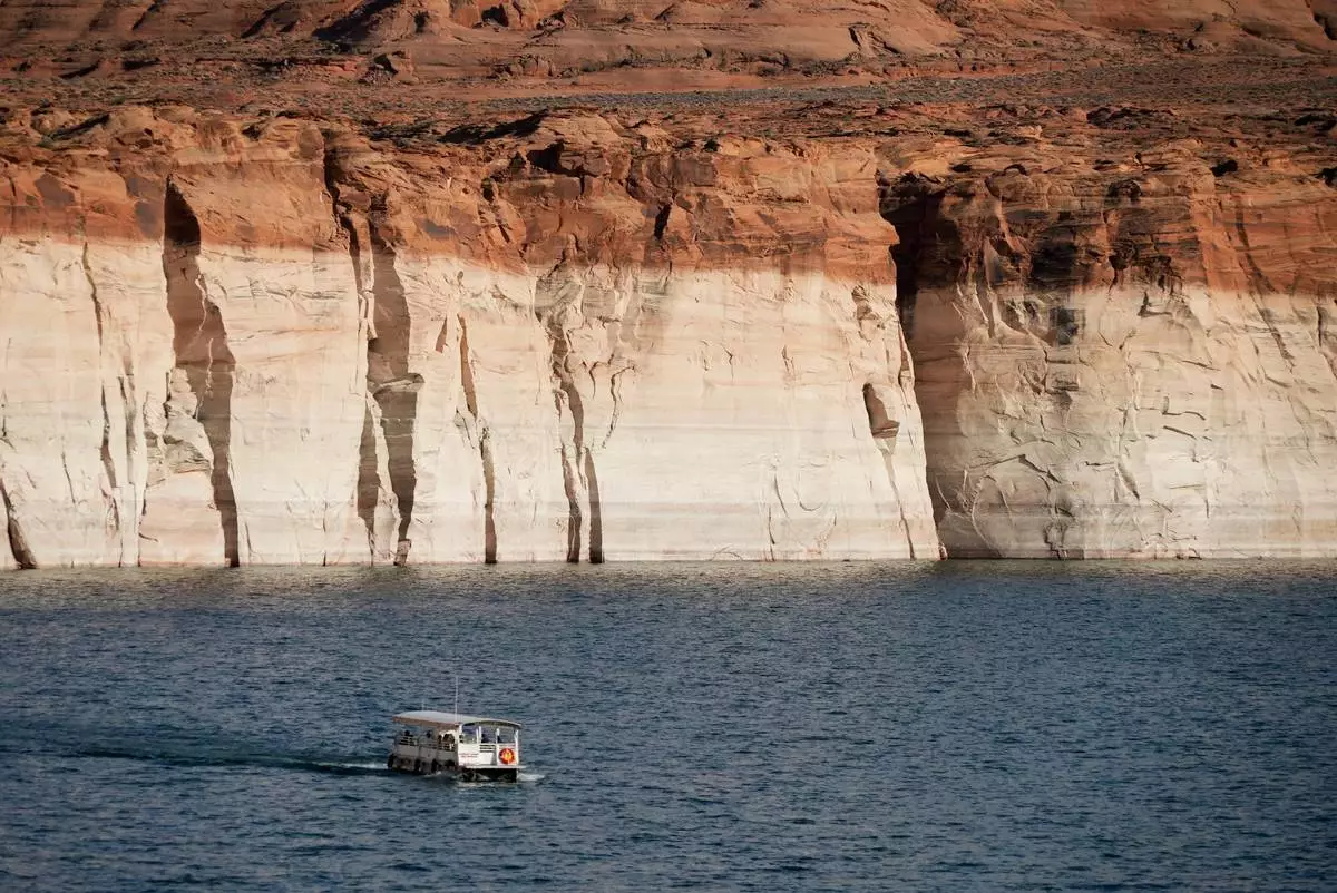 FILE - A boat floats past bathtub rings showing how low Lake Powell levels have dropped June 7, 2022, in Page, Ariz. (AP Photo/Brittany Peterson, File)