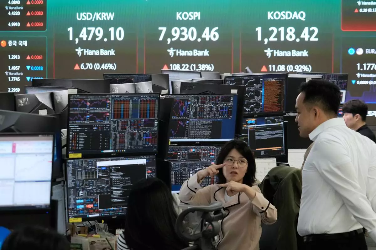Currency traders work near a screen showing the Korea Composite Stock Price Index (KOSPI), top center, and the foreign exchange rate between U.S. dollar and South Korean won, top center left, at the foreign exchange dealing room of the Hana Bank headquarters in Seoul, South Korea, Tuesday, May 12, 2026. (AP Photo/Ahn Young-joon)