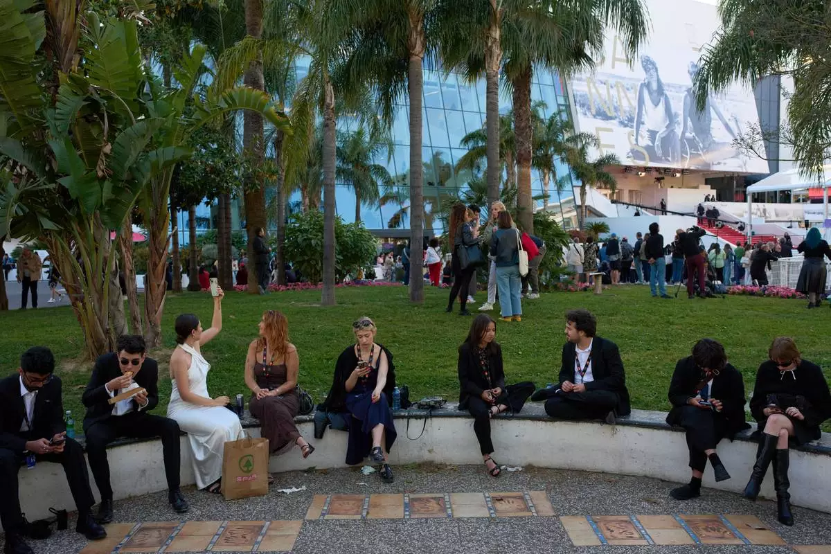 People wait outside before entering near the red carpet during the 79th international film festival, Cannes, southern France, Friday, May 15, 2026. (AP Photo/John Locher)