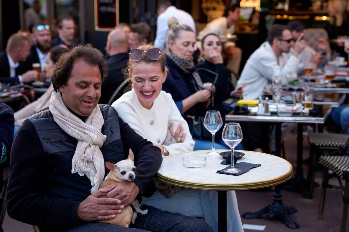 A man holds a dog in a bar during the 79th international film festival, Cannes, southern France, Tuesday, May 19, 2026. (AP Photo/Andreea Alexandru)