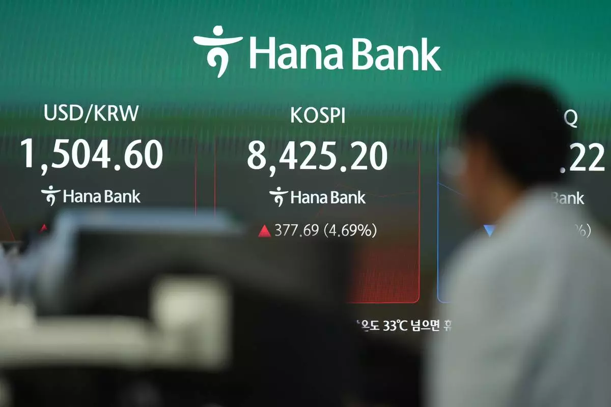 A dealer walks past near the screens showing the Korea Composite Stock Price Index (KOSPI) and the foreign exchange rate between U.S. dollar and South Korean won at a dealing room of Hana Bank in Seoul, South Korea, Wednesday, May 27, 2026. (AP Photo/Lee Jin-man)