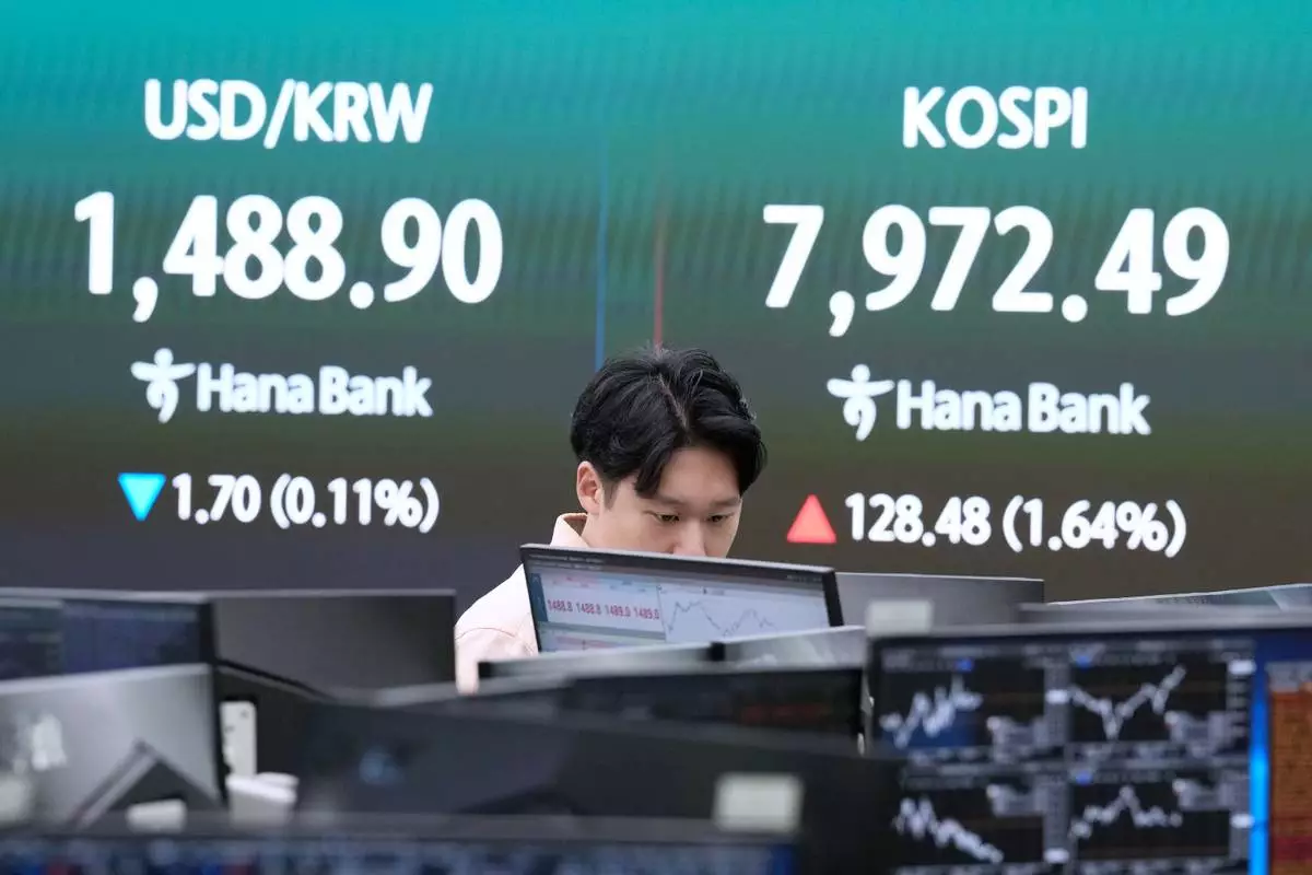 A currency trader watches monitors near a screen showing the Korea Composite Stock Price Index (KOSPI), right, and the foreign exchange rate between U.S. dollar and South Korean won at the foreign exchange dealing room of the Hana Bank headquarters in Seoul, South Korea, Thursday, May 14, 2026. (AP Photo/Ahn Young-joon)