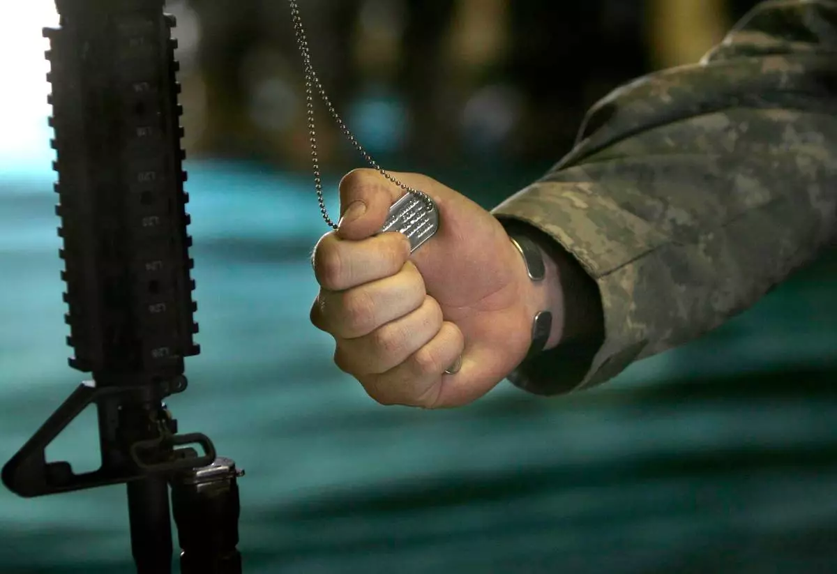 FILE - A U.S. soldier of the 82 Airborne Division holds the dog tag of Cpt. Davis Boris during a memorial ceremony at the forward operating base Bermel in Paktika, Afghanistan, Friday, Nov. 23, 2007. (AP Photo/Rafiq Maqbool, File)