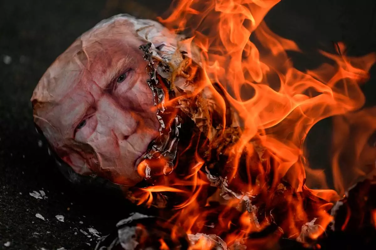 FILE - An effigy of President Donald Trump goes up in flames during an International Workers' Day march marking May Day in Panama City, May 1, 2026. (AP Photo/Matias Delacroix, File)