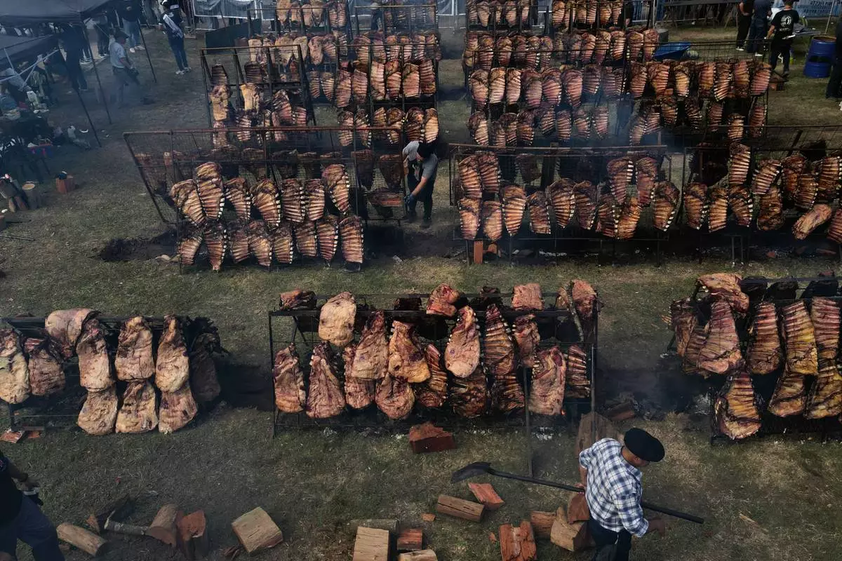 FILE - Workers cook Angus beef racks of ribs over a wood fire at the Creole Rib Festival in Uribelarrea, Argentina, May 1, 2026. (AP Photo/Natacha Pisarenko, File)