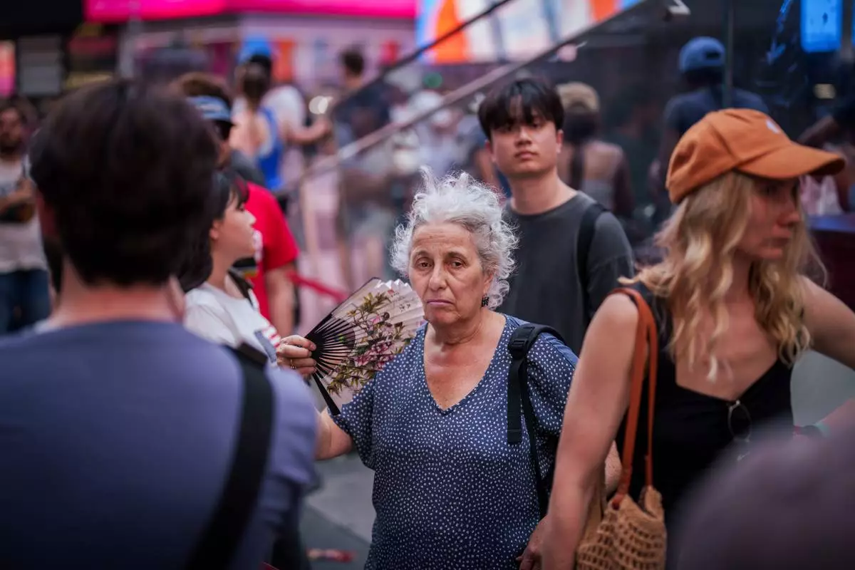 A person uses a fan as they wait in line to purchase Broadway tickets in Times Square, during a heat advisory in New York, Tuesday, May 19, 2026. (AP Photo/Adam Gray)
