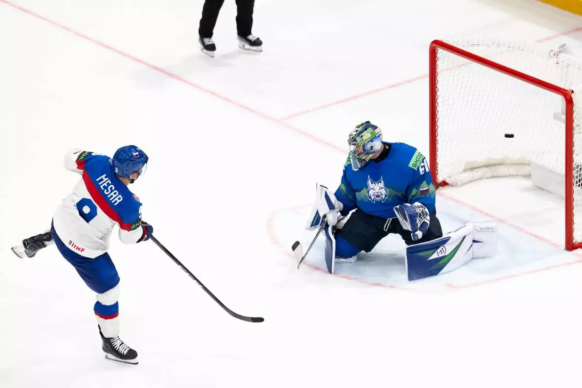 Slovakia's Filip Mesar, left, scores the winning goal past Slovenia's goaltender Lukas Horak during a shootout during the Group B preliminary round game between Italy and Norway at the men's ice hockey world Championship in Fribourg, Switzerland, Tuesday, May 19, 2026. (Anthony Anex/Keystone via AP)