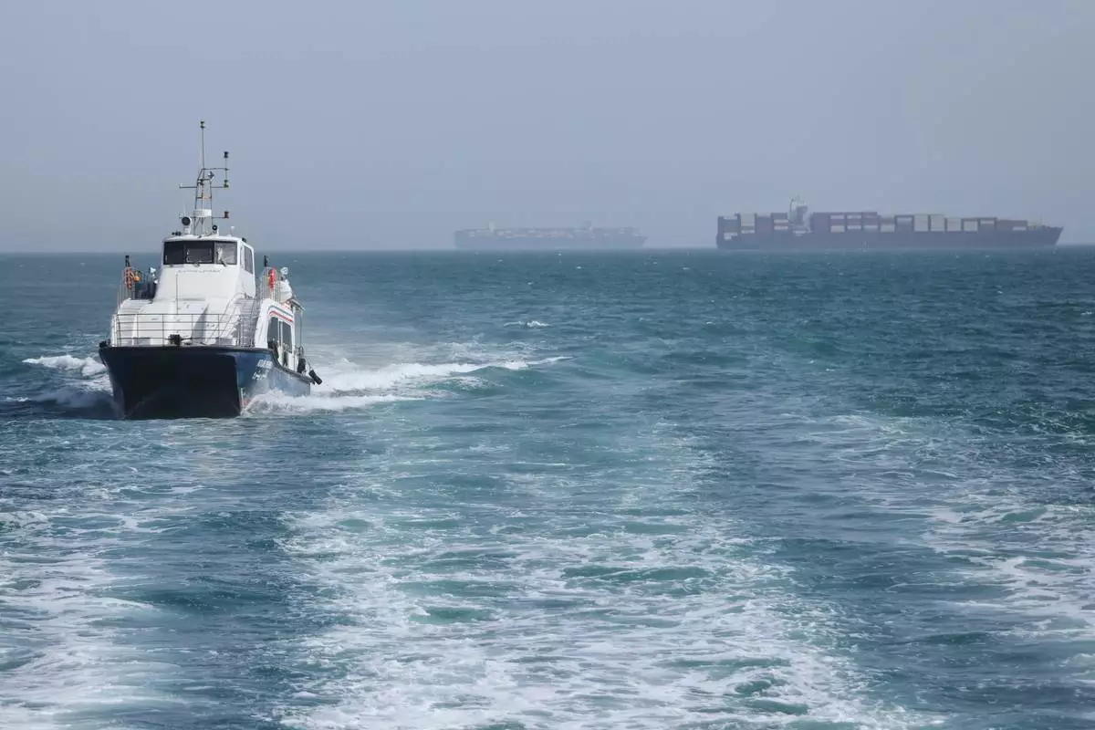 A patrol boat moves through the water as cargo ships sit at anchor in the Strait of Hormuz off Bandar Abbas, Iran, Saturday, May 2, 2026.(Amirhosein Khorgooi/ISNA via AP)