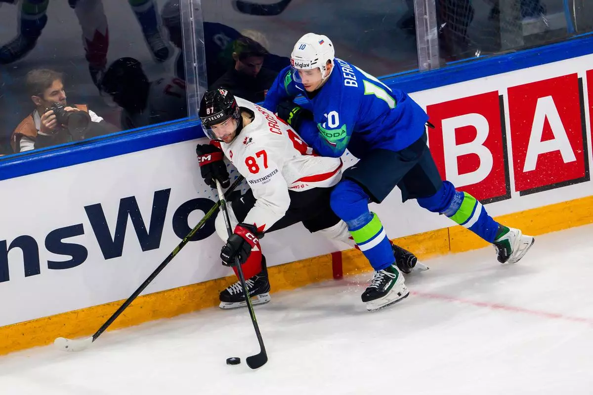 Canada's Sidney Crosby, left, vies for the puck against Slovenia's Miha Bericic, right, during a preliminary round game between Canada and Slovenia at the men's ice hockey world championship in Fribourg, Switzerland, Friday May 22, 2026. (Salvatore Di Nolfi/Keystone via AP)