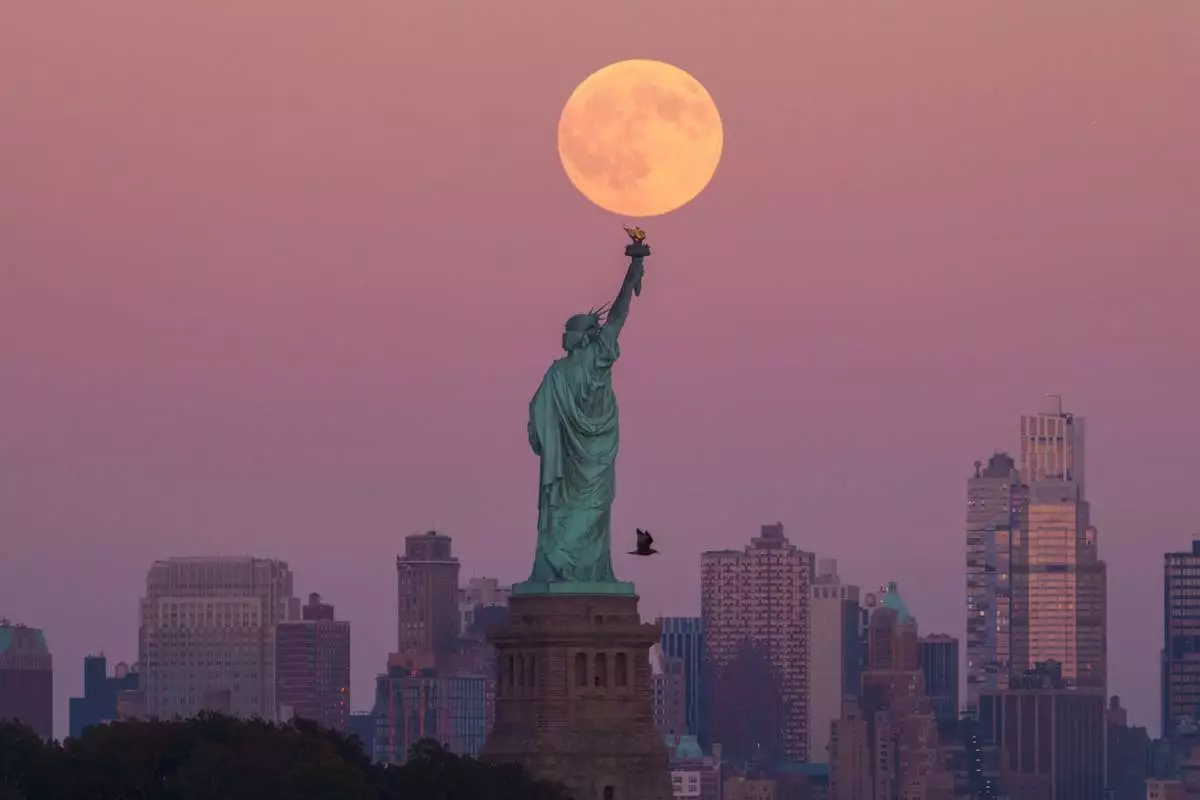 FILE - The Harvest Supermoon rises behind the Statue of Liberty and the Brooklyn skyline, Oct. 6, 2025, in Jersey City, N.J. (AP Photo/Adam Gray, File)