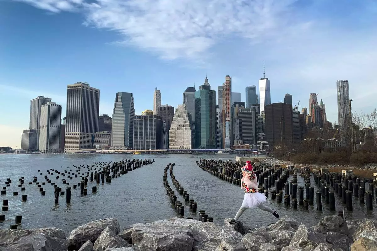 FILE - With One World Trade Center seen in the background, a little girl leaps across boulders forming a breakwater along the Brooklyn Bridge Park on Dec. 27, 2018, in the Brooklyn borough, of New York. (AP Photo/Wong Maye-E, File)
