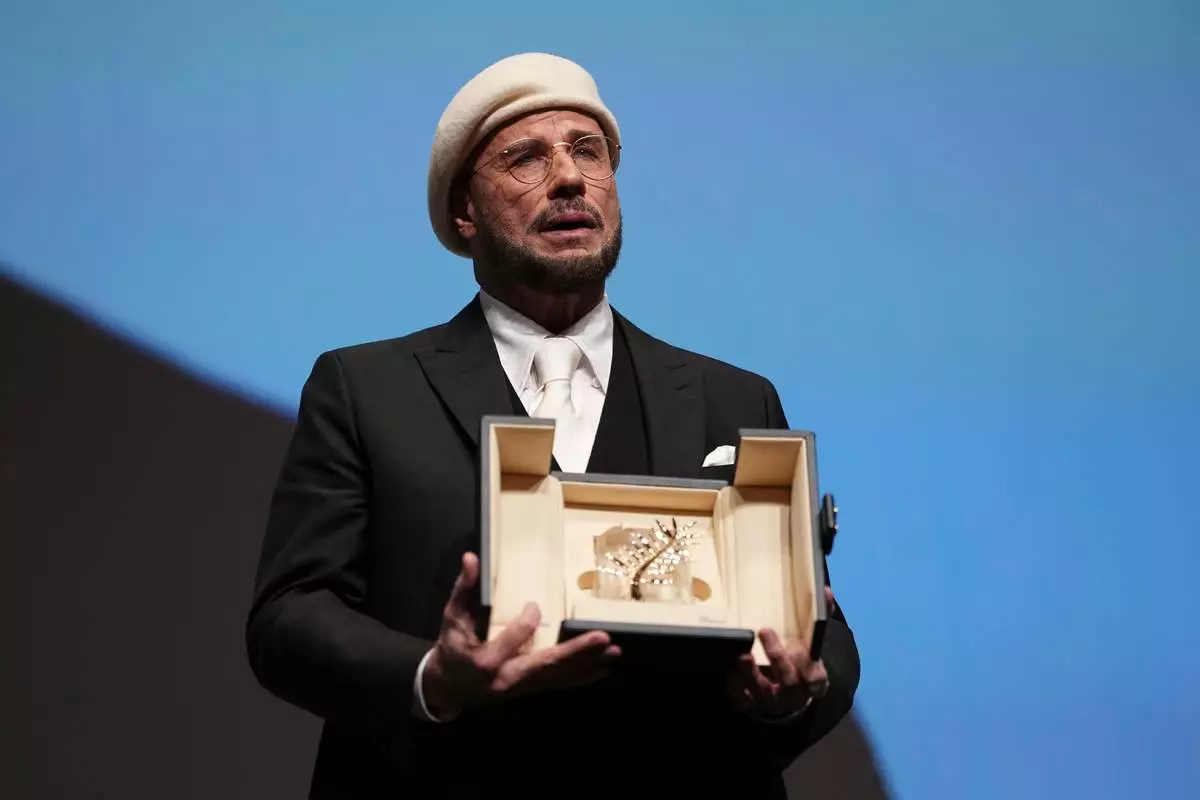 John Travolta holds his honorary Palme d'Or during the 79th international film festival, Cannes, southern France, Friday, May 15, 2026. (Photo by Scott A Garfitt/Invision/AP)