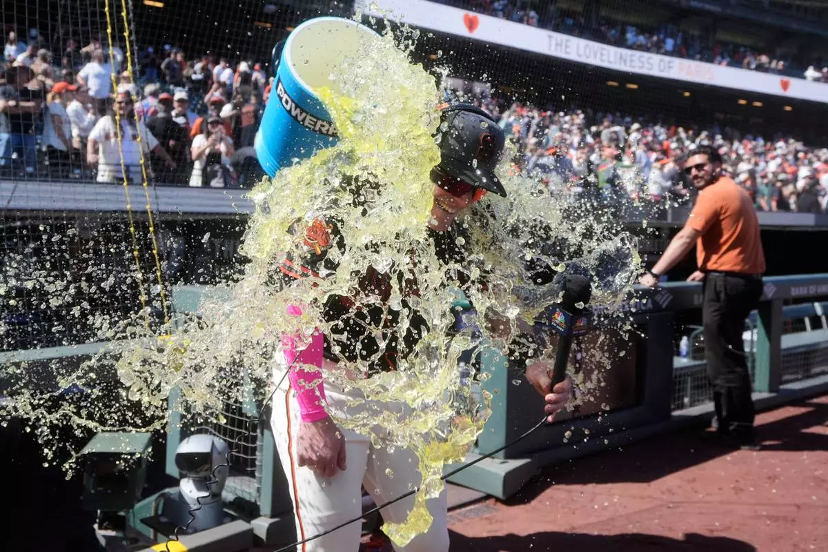 San Francisco Giants' Harrison Bader is doused by Willy Adames while being interviewed after a baseball game against the Chicago White Sox Saturday, May 23, 2026, in San Francisco. (AP Photo/Jeff Chiu)