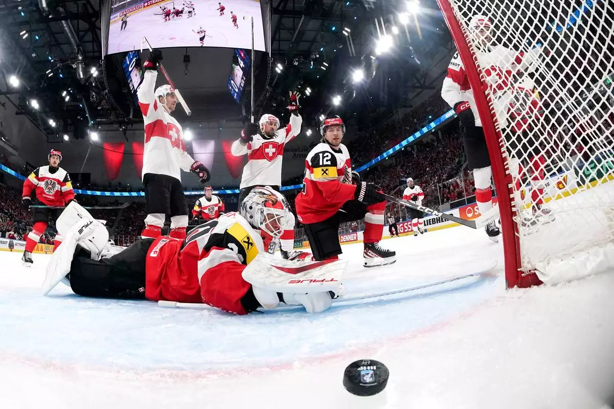 Switzerland's Nico Hischier, right, scores the fifth goal to Austria's goaltender David Kickert, left, during the 2026 IIHF Men's Ice Hockey World Championship preliminary round group A game between Austria and Switzerland, in Zurich, Switzerland, Wednesday, May 20, 2026. (Claudio Thoma/Keystone via AP)