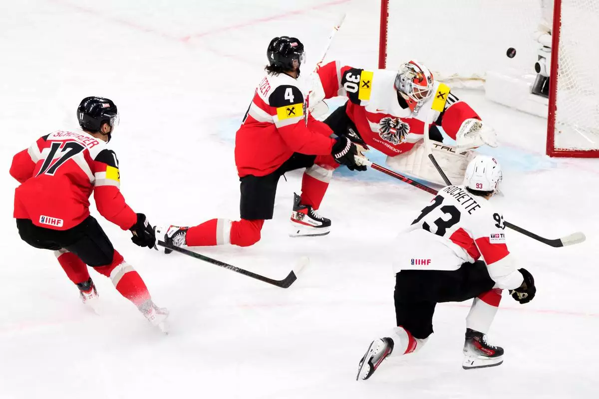 Switzerland's Theo Rochette, right in white, scores the teams first goal against, from left, Austria's Ian Scherzer, Austria's Ramon Schnetzer and Austria's goaltender David Kickert during the 2026 IIHF Men's Ice Hockey World Championship preliminary round group A game between Austria and Switzerland, in Zurich, Switzerland, Wednesday, May 20, 2026. (Claudio Thoma/Keystone via AP)