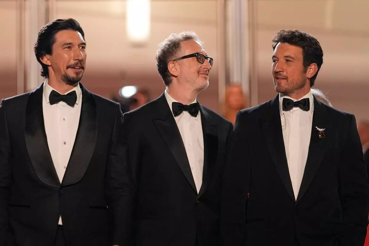 Adam Driver, left, director James Gray and Miles Teller pose for photographers upon arrival at the premiere of the film 'Paper Tiger' at the 79th international film festival, Cannes, southern France, Saturday, May 16, 2026. (AP Photo/John Locher)