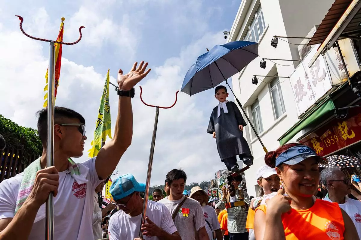 A child is hoisted up during the Piu Sik Parade at the Bun Festival in Cheung Chau Island in Hong Kong, Sunday, May 24, 2026. (AP Photo/Chan Long Hei)