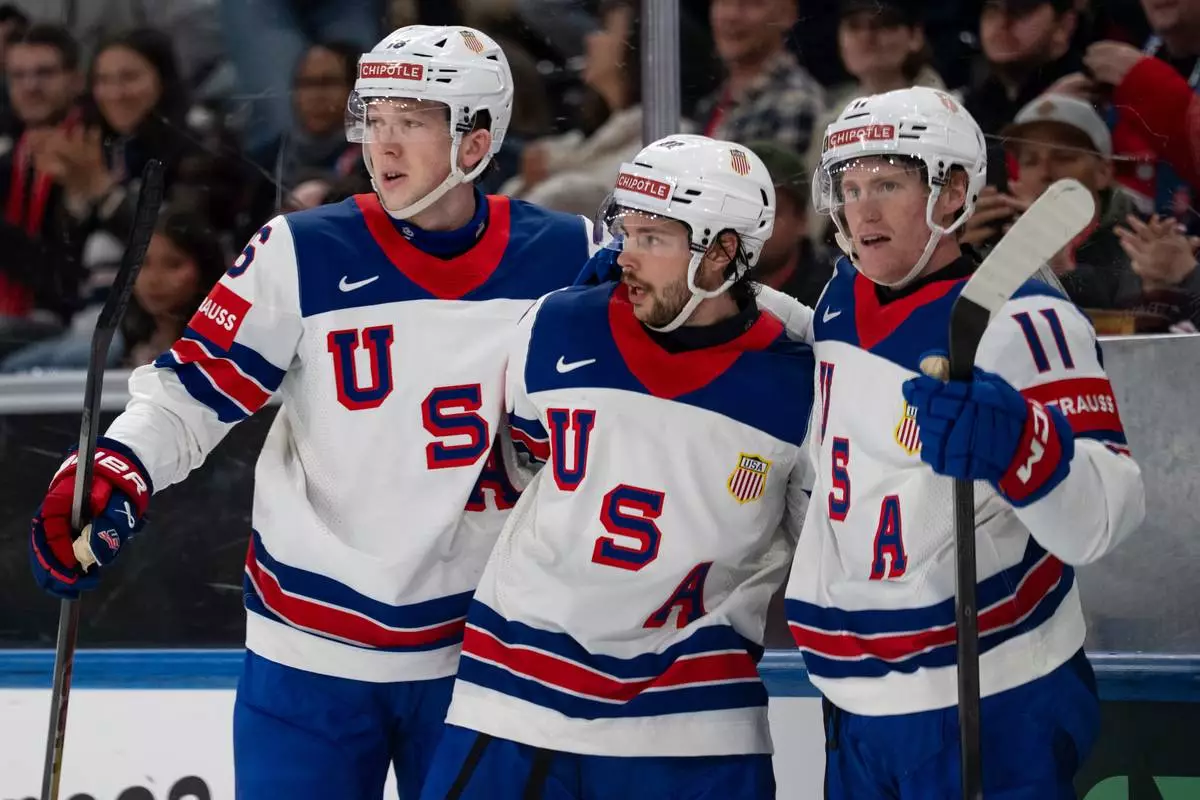 From left, USA's Mason Lohrei, Isaac Howard and Oliver Moore celebrate after their team's second goal, during the 2026 IIHF Men's Ice Hockey World Championship preliminary round group A game between Britain and the United States, in Zurich, Switzerland, Sunday, May 17, 2026. (Claudio Thoma/Keystone via AP)