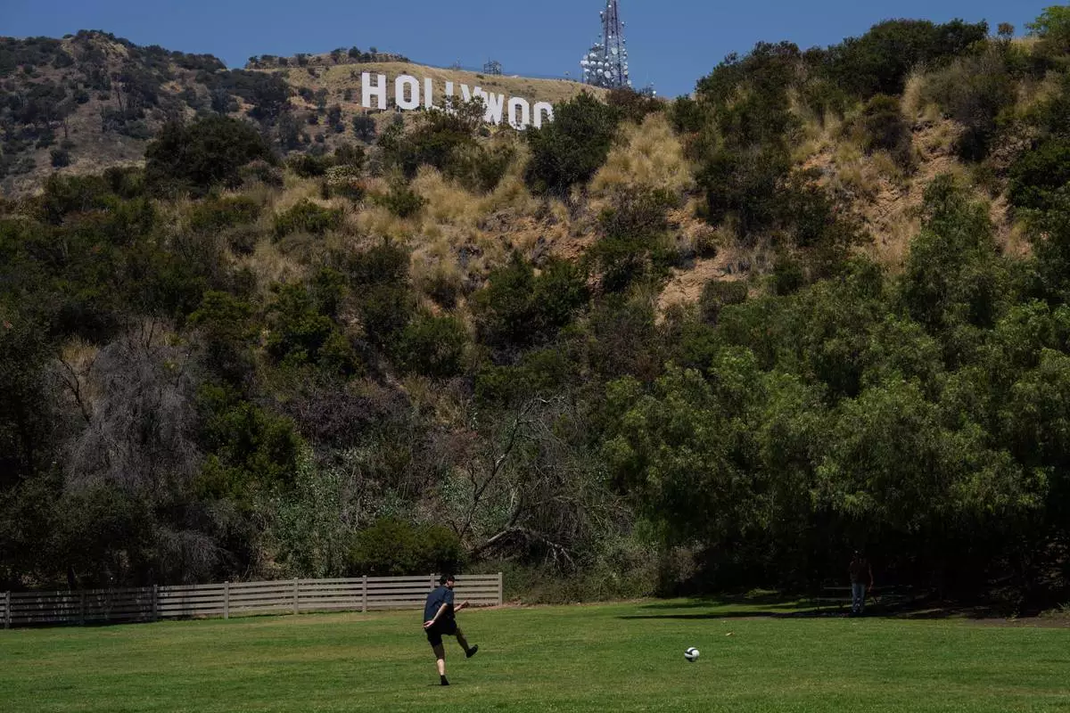 A person kicks a soccer ball in a park beneath the Hollywood sign in Los Angeles, May 8, 2026. (AP Photo/Jae C. Hong)