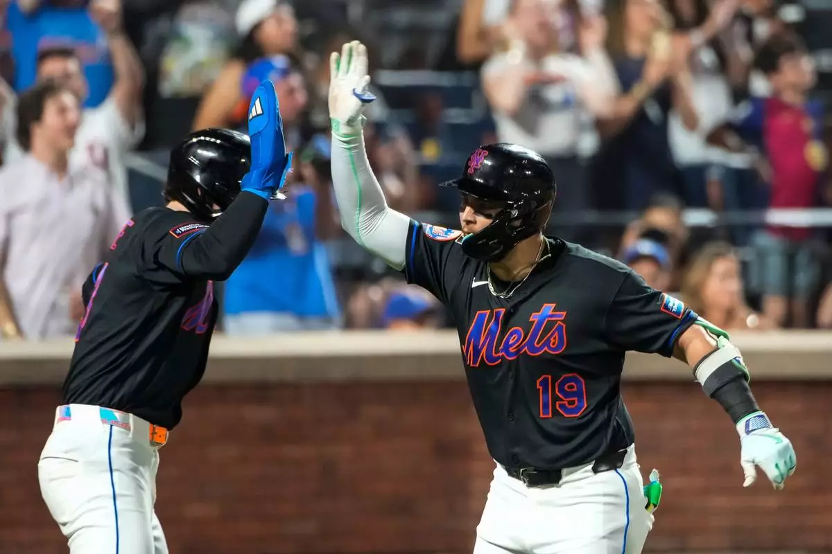 New York Mets' Bo Bichette (19) celebrates a solo home run with a teammate during the second inning of a baseball game against the Atlanta Braves, Friday, June 12, 2026, in New York. (AP Photo/Eduardo Munoz Alvarez) CORRECTION: Atlanta Braves is correct instead of St. Louis Cardinals