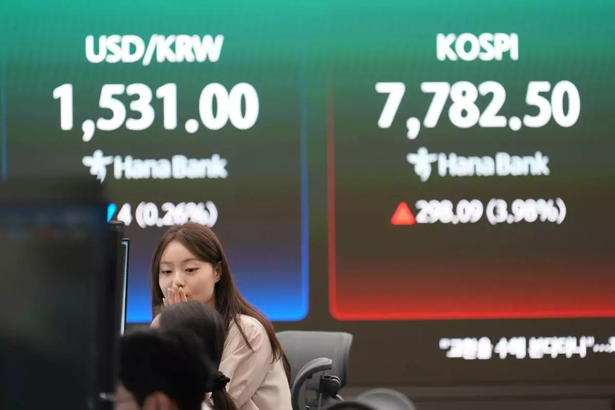 A dealer talks near the screens showing the Korea Composite Stock Price Index (KOSPI) and the foreign exchange rate between U.S. dollar and South Korean won at a dealing room of Hana Bank in Seoul, South Korea, Tuesday, June 9, 2026. (AP Photo/Lee Jin-man)