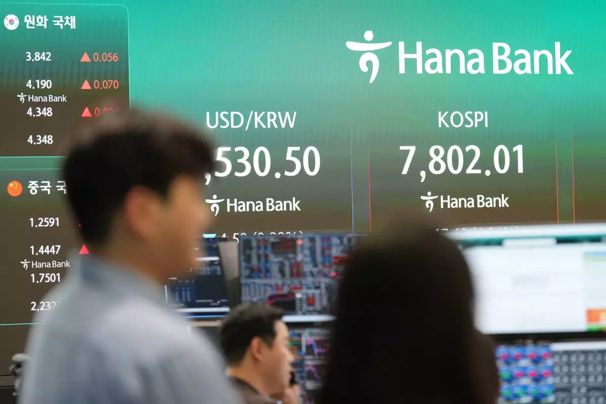 People stand near the screens showing the Korea Composite Stock Price Index (KOSPI) and the foreign exchange rate between U.S. dollar and South Korean won at a dealing room of Hana Bank in Seoul, South Korea, Tuesday, June 9, 2026. (AP Photo/Lee Jin-man)
