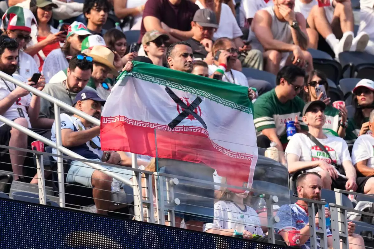 An attendees holds an Iranian flag with an "X" on it before the World Cup Group G soccer match between Iran and New Zealand in Inglewood, Calif., near Los Angeles, Monday, June 15, 2026. (AP Photo/Mark J. Terrill)