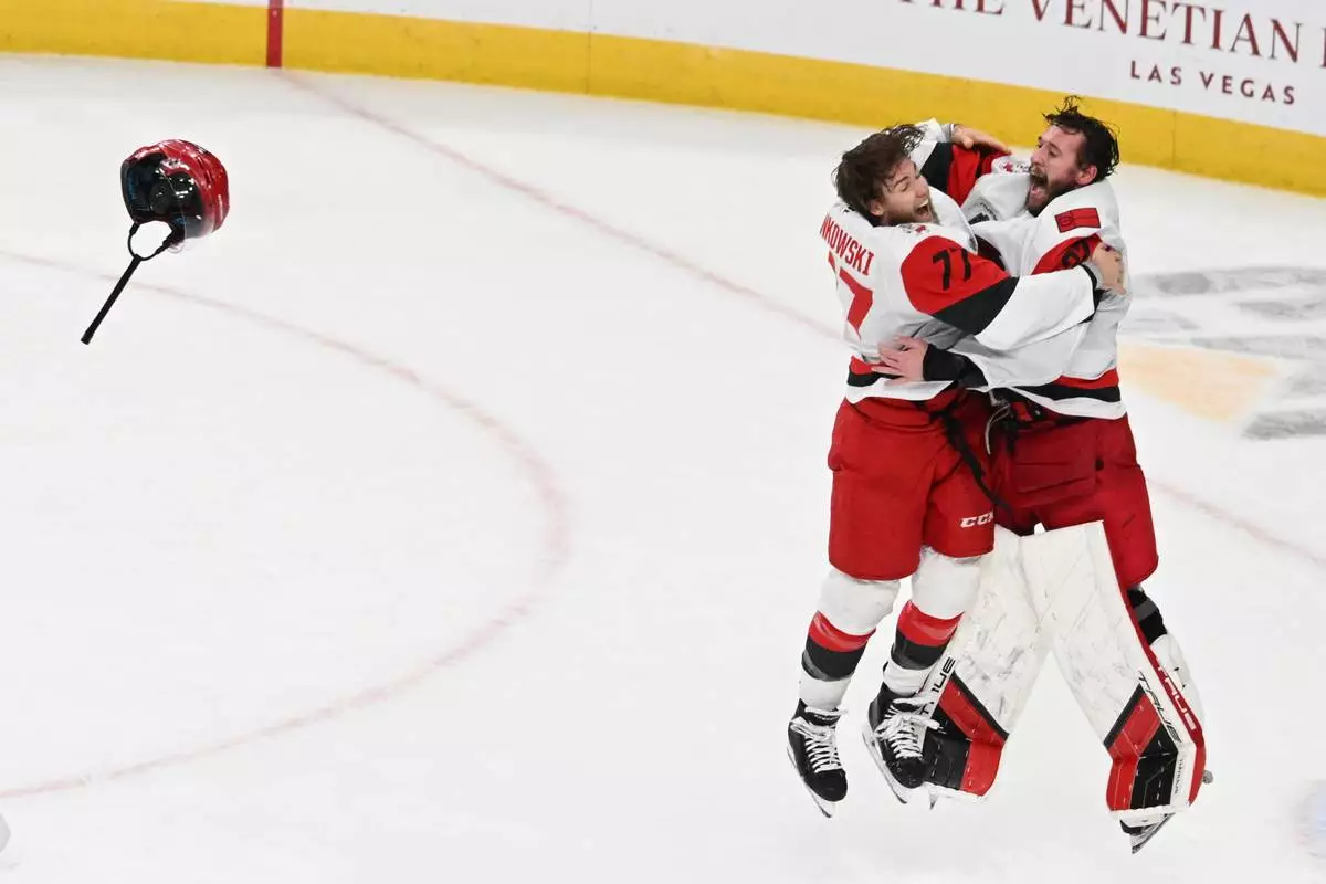 Carolina Hurricanes left wing Mark Jankowski (77) and goaltender Brandon Bussi (32) celebrate after a win over the Vegas Golden Knights in Game 6 of the NHL hockey Stanley Cup Final series, Sunday, June 14, 2026, in Las Vegas. (AP Photo/Candice Ward)