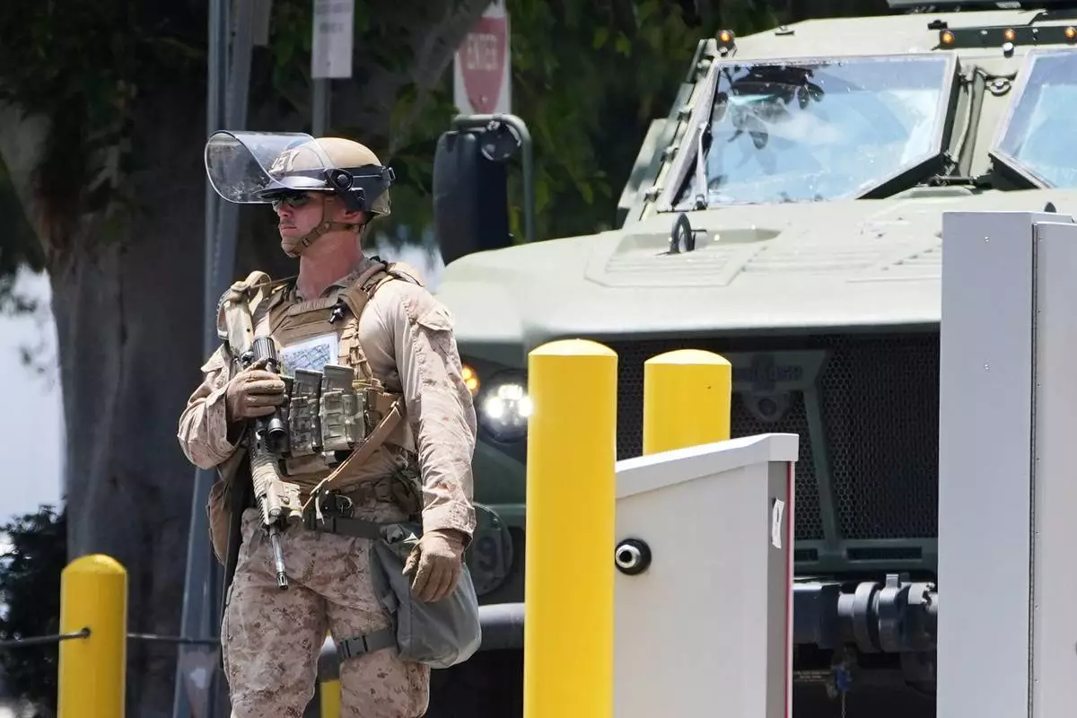 FILE - A U.S. Marine patrols outside of a federal building, June 13, 2025, in Los Angeles (AP Photo/Damian Dovarganes, File)