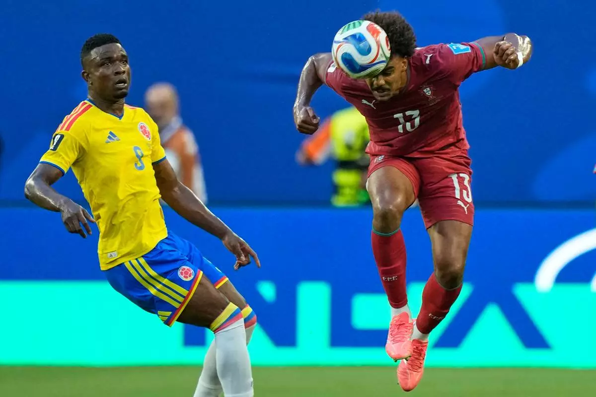 Portugal's Renato Veiga (13) heads the ball as Colombia's Jhon Cordoba (9) watches during the World Cup Group K soccer match between Colombia and Portugal in Miami Gardens, Fla., Saturday, June 27, 2026. (AP Photo/Rebecca Blackwell)