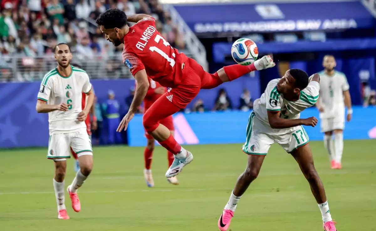 Jordan's Mahmoud Almardi (13) tries to hit the ball back up field against Algeria's Rafik Belghali (17) during the first half of the World Cup Group J soccer match in Santa Clara, Calif., near San Francisco, Monday, June 22, 2026. (Carlos Avila Gonzalez/San Francisco Chronicle via AP)