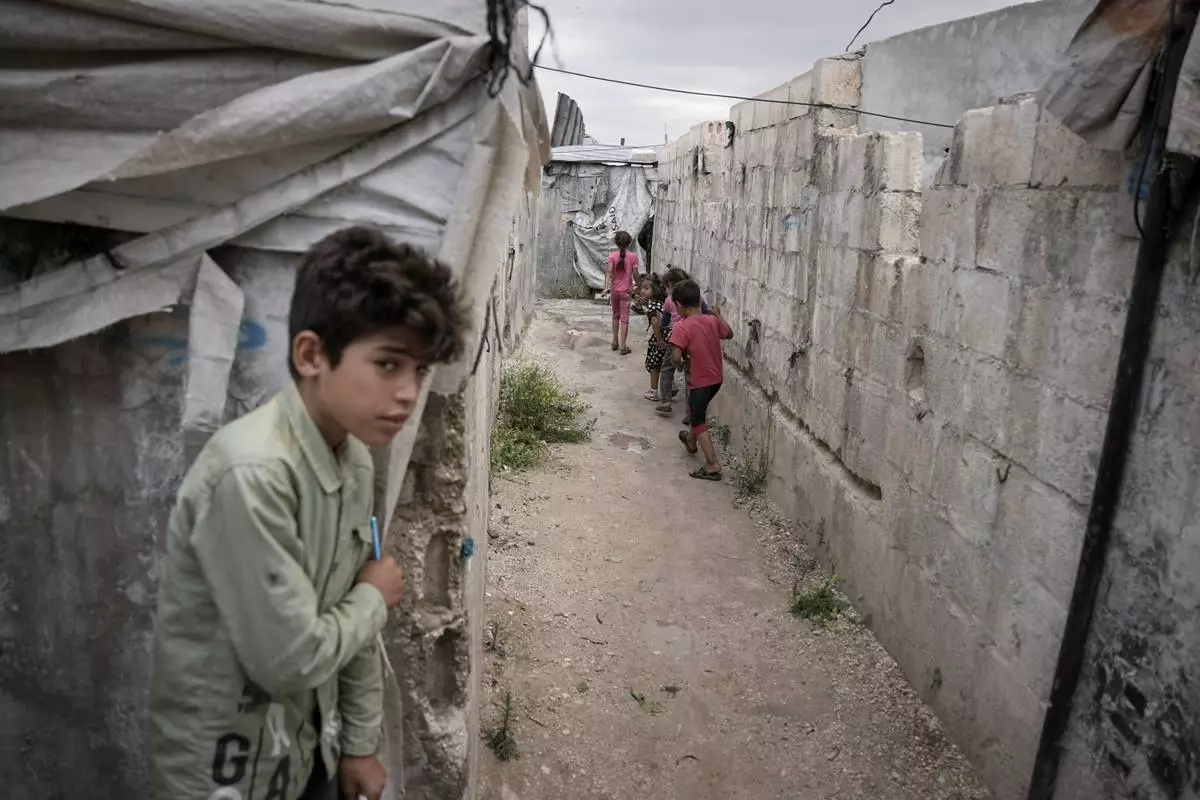 FILE - Children play through al-Karama camp, established in the early years of the Syrian conflict and built from scratch with light-brick structures covered with fabric to house internally displaced Syrians near the village of Atmeh, Idlib province, Syria, May 19, 2026. (AP Photo/Omar Albam, File)