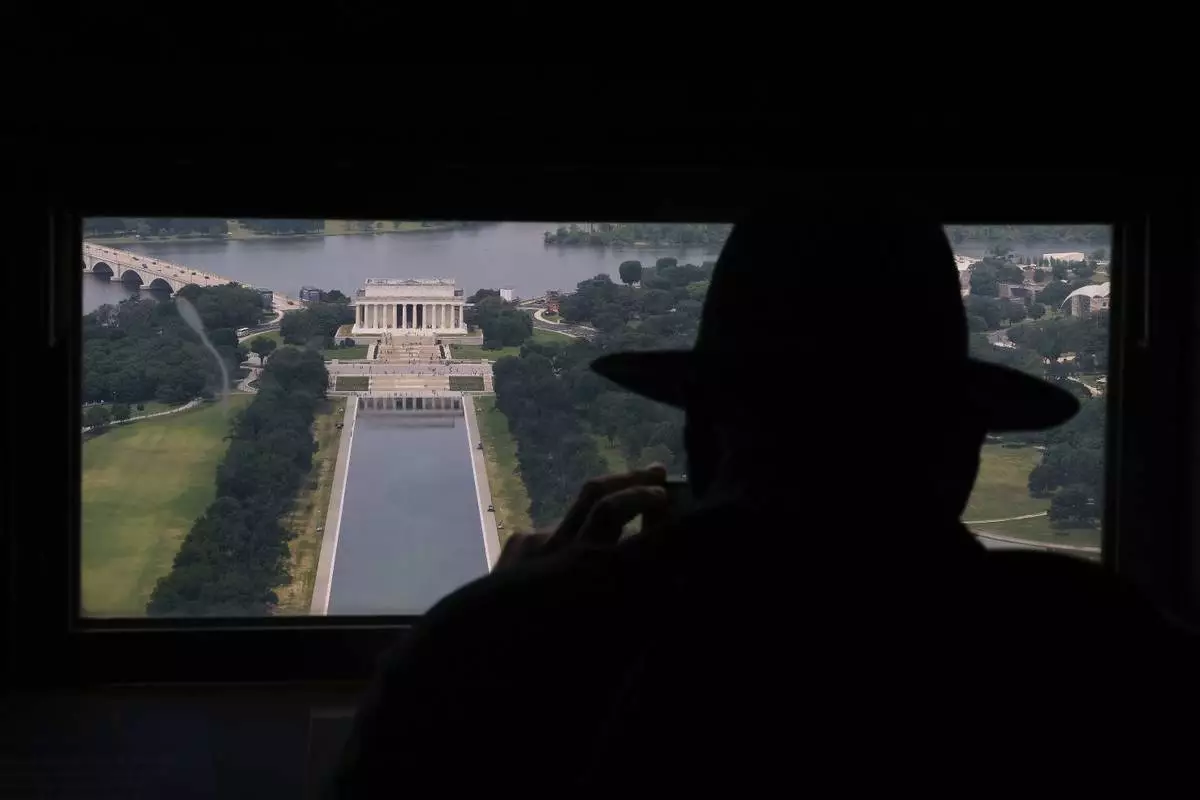 David Boczar photographs the Lincoln Memorial and the Lincoln Memorial Reflecting Pool from a window at the top of the Washington Monument, Friday, June 26, 2026, in Washington. (AP Photo/Carolyn Kaster)