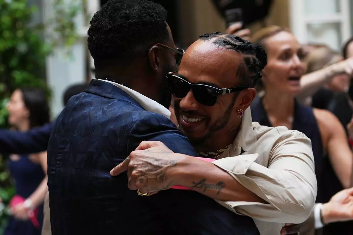 Lewis Hamilton, right hugs Colman Domingo as he arrives for the Ralph Lauren Spring/Summer 2027 men's collection, presented in Milan, Italy, Friday, June 19, 2026. (AP Photo/Antonio Calanni)