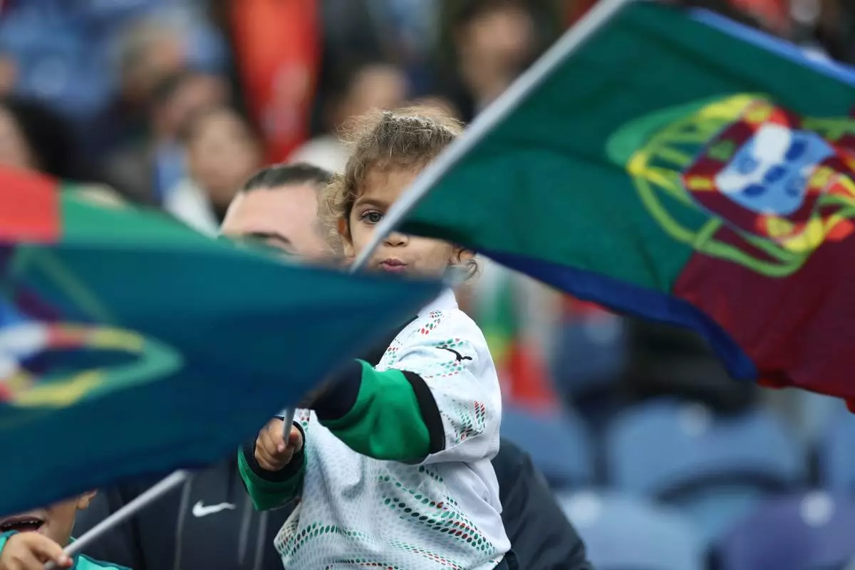 FILE - Children on the stands wave Portuguese flags before a World Cup 2026 group F qualifying soccer match between Portugal and Armenia in Porto, Portugal, Sunday, Nov. 16, 2025. (AP Photo/Luis Vieira,File)