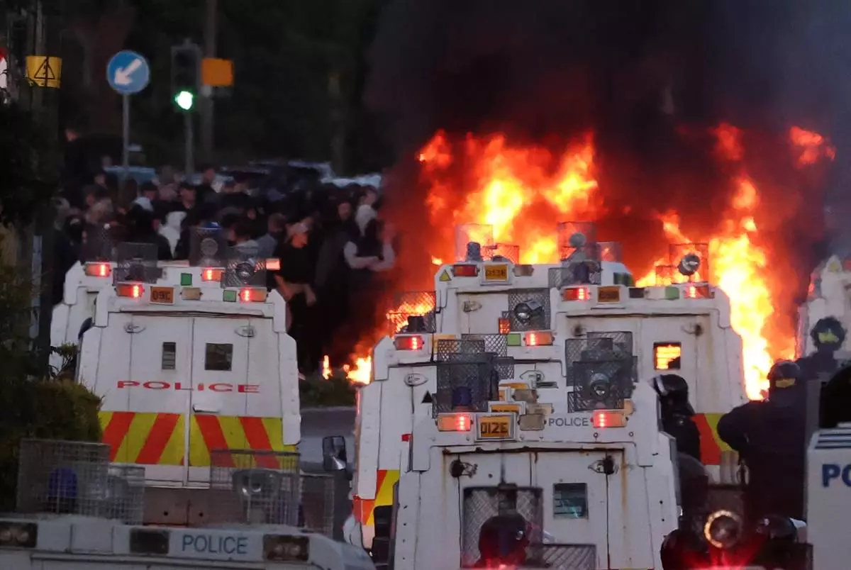 Police attempt to disperse protesters as a fire burns near Newtownabbey, in Belfast, Northern Ireland, Wednesday, June 10, 2026, following a stabbing incident on Monday night. (PA via AP)