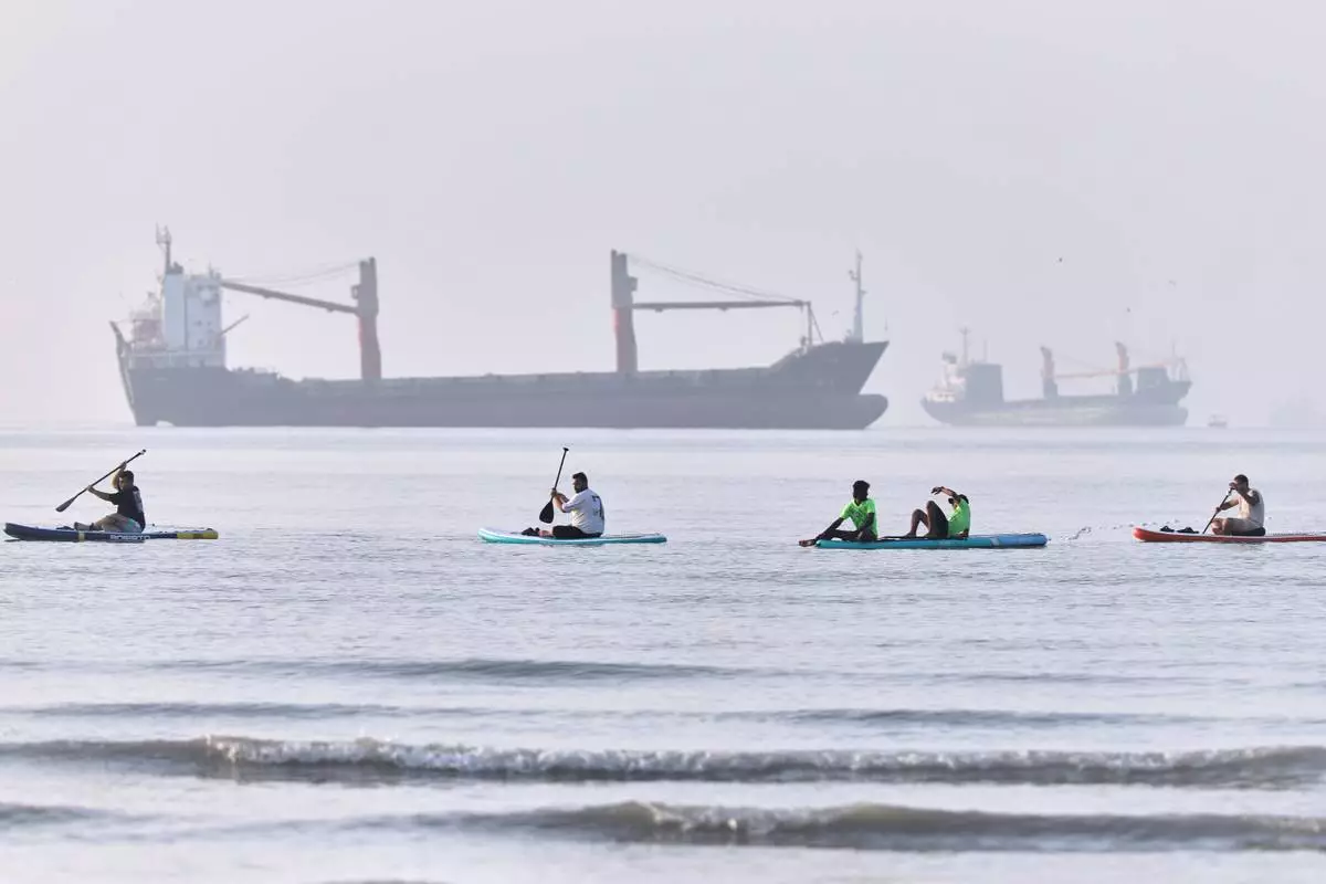 People paddle along the shoreline as cargo ships are anchored in the Strait of Hormuz off Bandar Abbas, Iran, Monday, June 1, 2026. (Amirhosein Khorgooi/ISNA via AP)