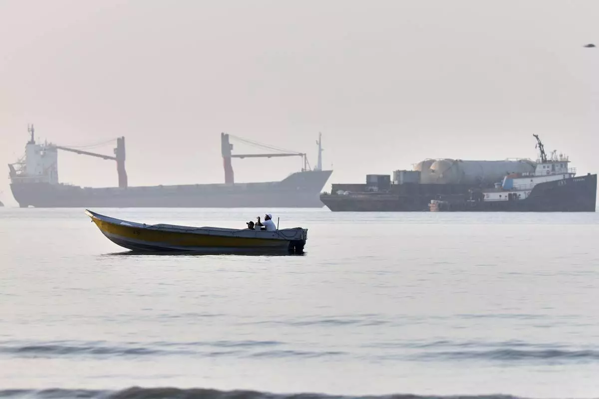 A small boat moves along the shoreline where an a cargo vessel, tugboat and industrial barge are all anchored in the Strait of Hormuz off Bandar Abbas, Iran, Monday, June 1, 2026. (Amirhosein Khorgooi/ISNA via AP)