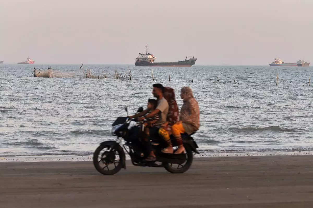 Cargo and service vessels line the horizon as people ride a motorcycle along the Strait of Hormuz, off Bandar Abbas, Iran, Sunday, May 31, 2026. (Amirhosein Khorgooi/ISNA via AP)