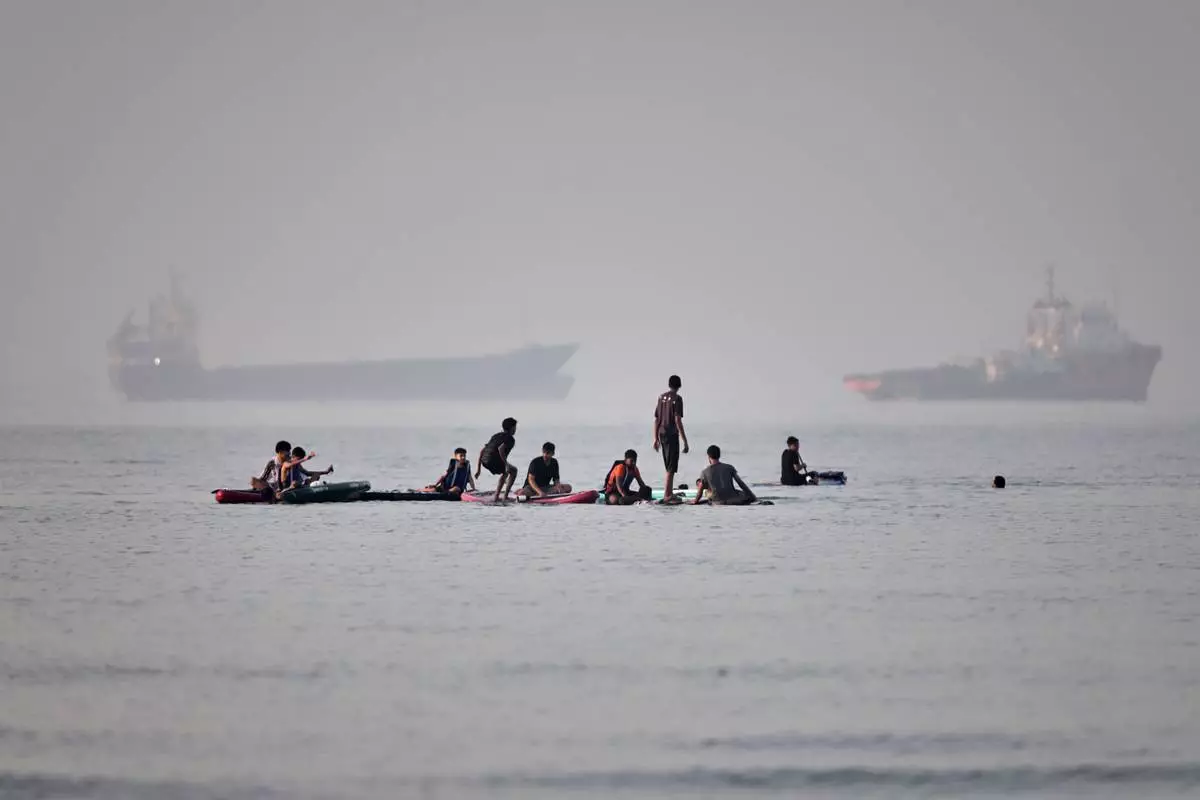 People gather on paddleboards in shallow water as cargo and service vessels are anchored in the Strait of Hormuz off Bandar Abbas, Iran, Monday, June 1, 2026. (Amirhosein Khorgooi/ISNA via AP)