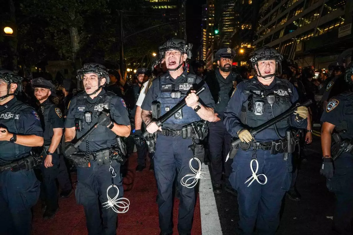 NYPD officers push New York Knicks fans back outside of a watch party in Bryant Park for Game 3 of the NBA Finals basketball series between the Knicks and the San Antonio Spurs, Monday, June 8, 2026, in New York. (AP Photo/Ryan Murphy)
