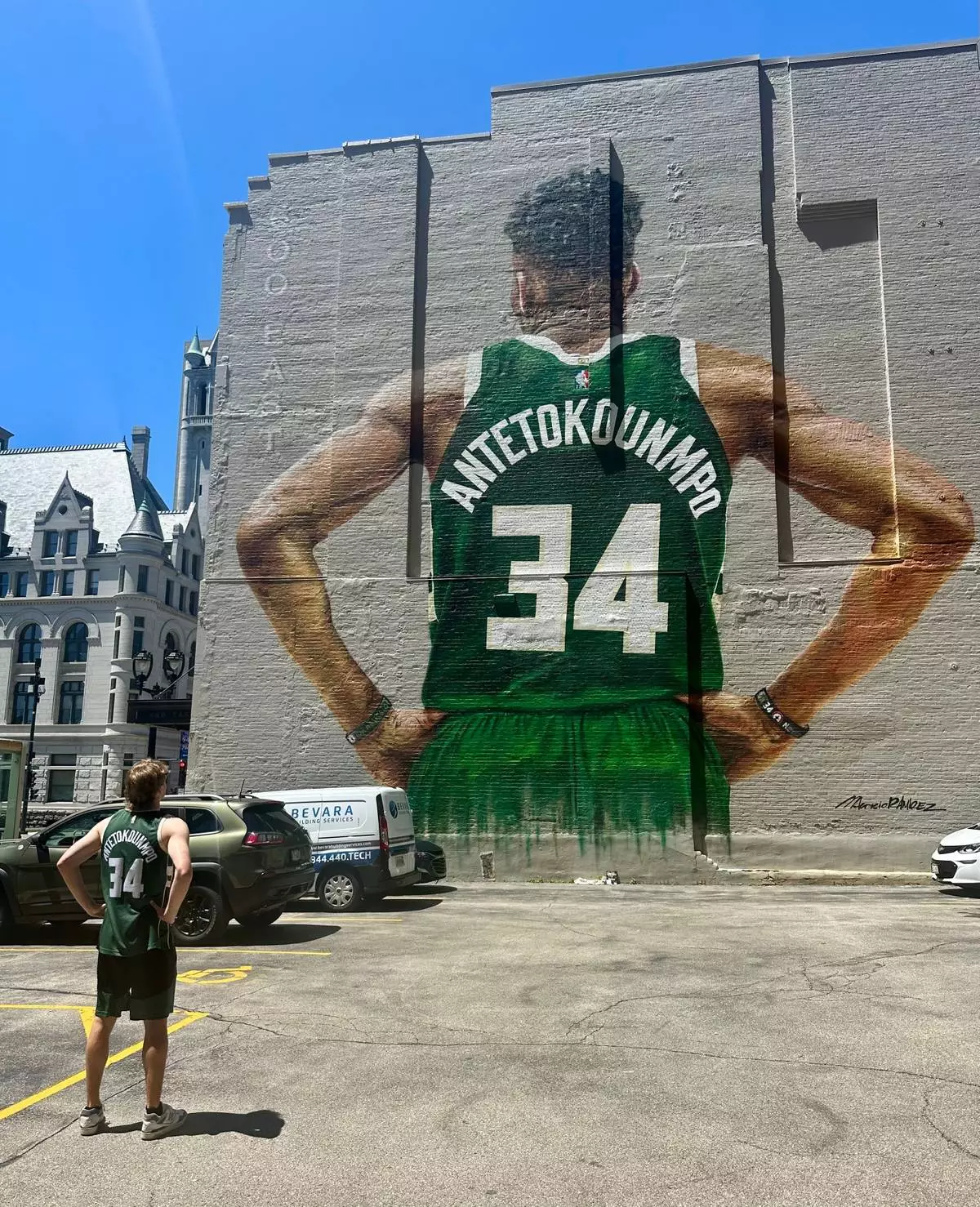 Danny Nelson wears a Giannis Antetokounmpo Milwaukee Bucks jersey while staring at a mural of him in downtown Milwaukee on Tuesday, June 23, 2026. (AP Photo/Steve Megargee)