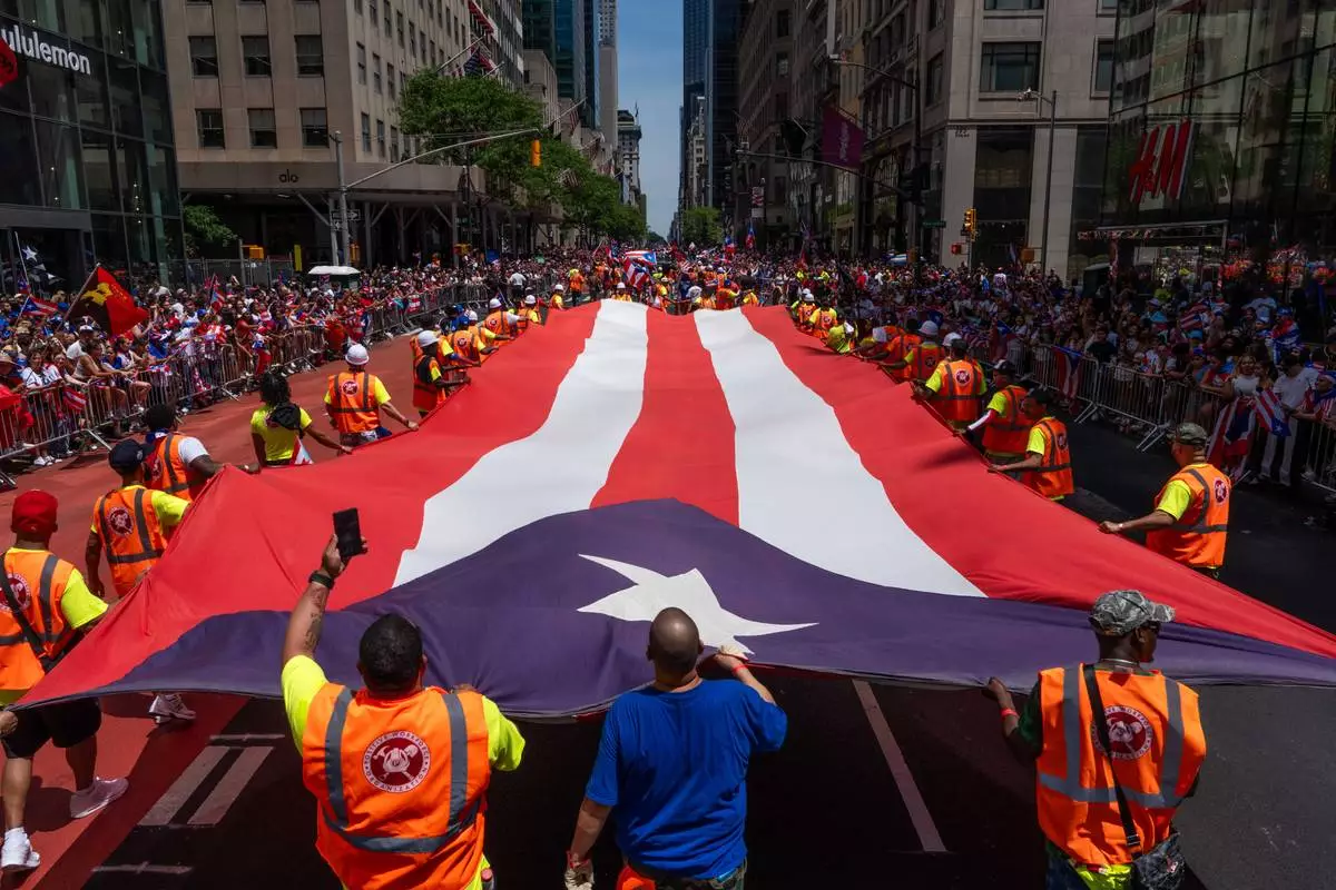 A giant Puerto Rican flag is carried during the National Puerto Rican Day Parade, Sunday, June 14, 2026 in New York. (AP Photo/Adam Gray)