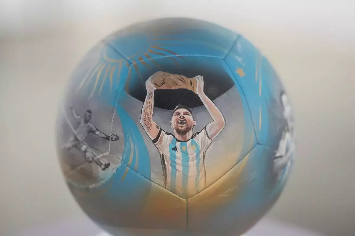 Lionel Messi lifting a trophy is depicted on a soccer ball hand-painted by artist Lili Cantero to commemorate Argentina's 2022 World Cup victory in Qatar, part of a neighborhood-wide soccer ball art trail and World Cup-themed treasure hunt planned for Miami's Wynwood district, Thursday, June 4, 2026. (AP Photo/Rebecca Blackwell)