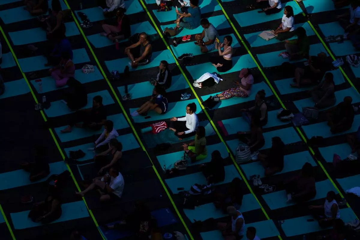 People participate in a mass yoga class during the "Times Square: Mind Over Madness Yoga" event, to celebrate the summer solstice, Sunday, June. 21, 2026, in New York (AP Photo/Adam Gray)