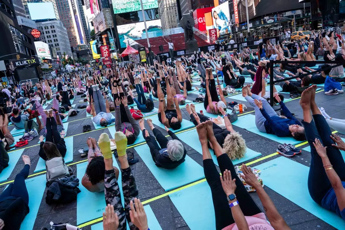 People participate in a mass yoga class during the "Times Square: Mind Over Madness Yoga" event, to celebrate the summer solstice, Sunday, June. 21, 2026, in New York (AP Photo/Adam Gray)