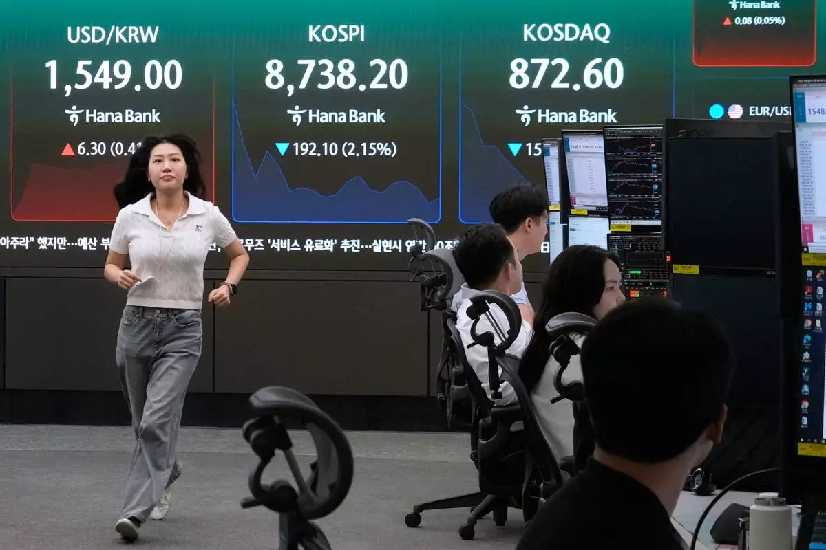 A currency trader passes by a screen showing the Korea Composite Stock Price Index (KOSPI) and the foreign exchange rate between U.S. dollar and South Korean won at the foreign exchange dealing room of the Hana Bank headquarters in Seoul, South Korea, Friday, June 26, 2026. (AP Photo/Ahn Young-joon)