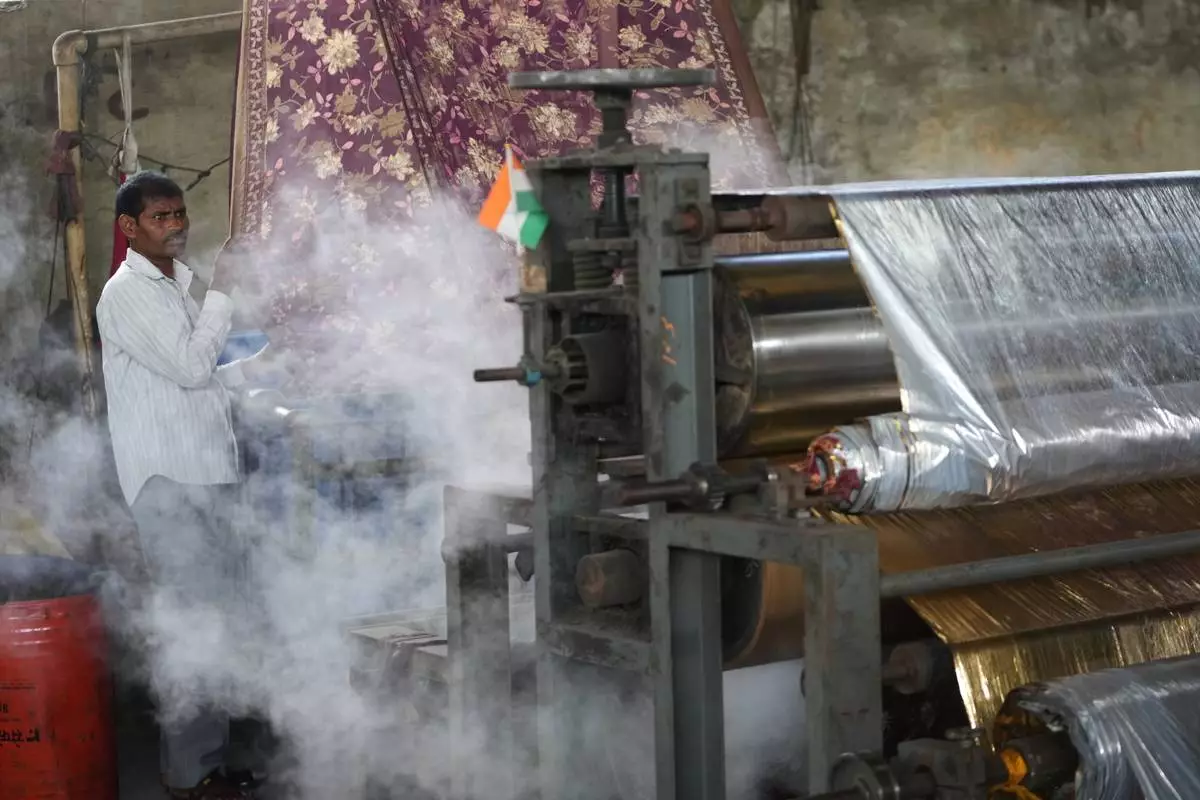 Steam comes out of a machine near a worker at a textile factory on a hot day in Sachin near Surat, India, Wednesday, May 27, 2026. (AP Photo/Ajit Solanki)
